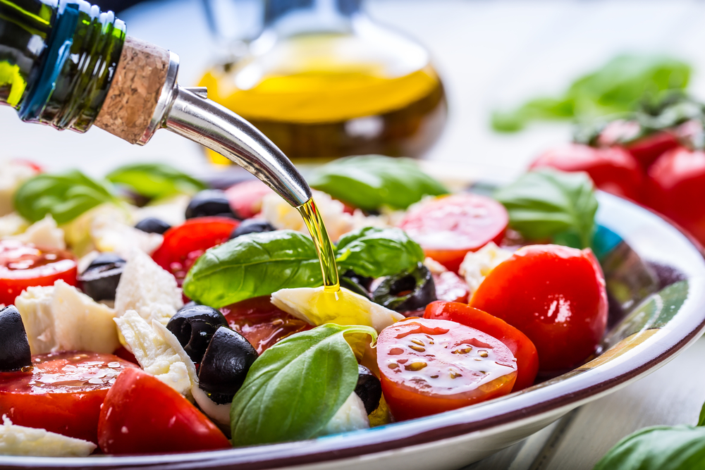 A fresh and healthy salad full of tomatoes, olives, cheeses, full of olive oil 