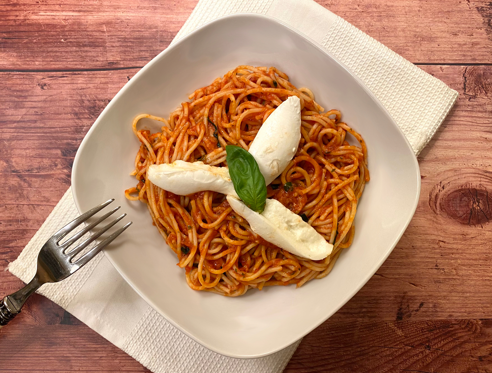 pieces of cheese on top of red pasta on a plate with a fork on the side