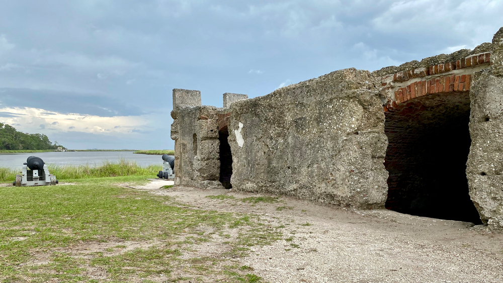a historic stone structure on the water with cannons lining the water behind the structure
