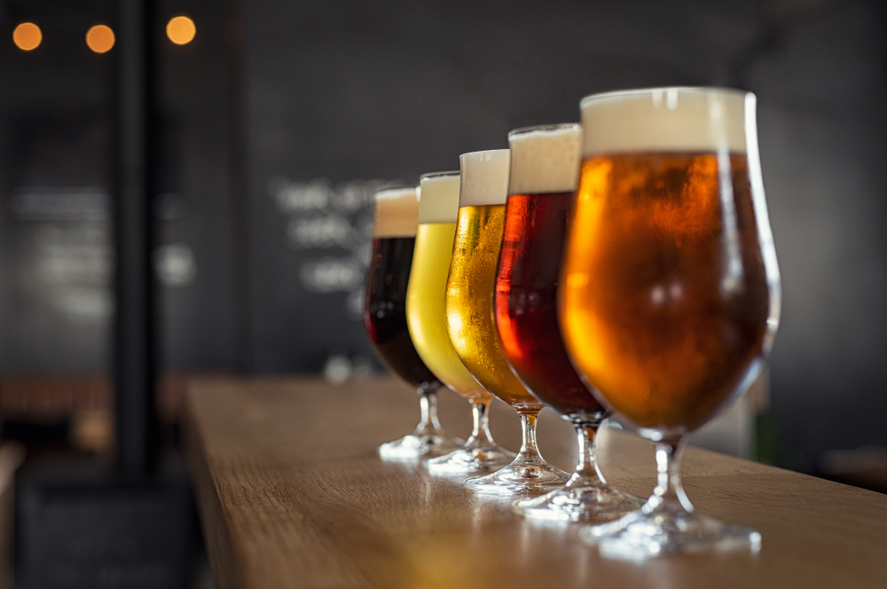 a line of beer glasses sitting on a bar, the background is blurry 
