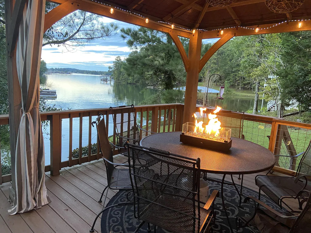 view of the deck with firepit and table overlooking the beautiful lake 