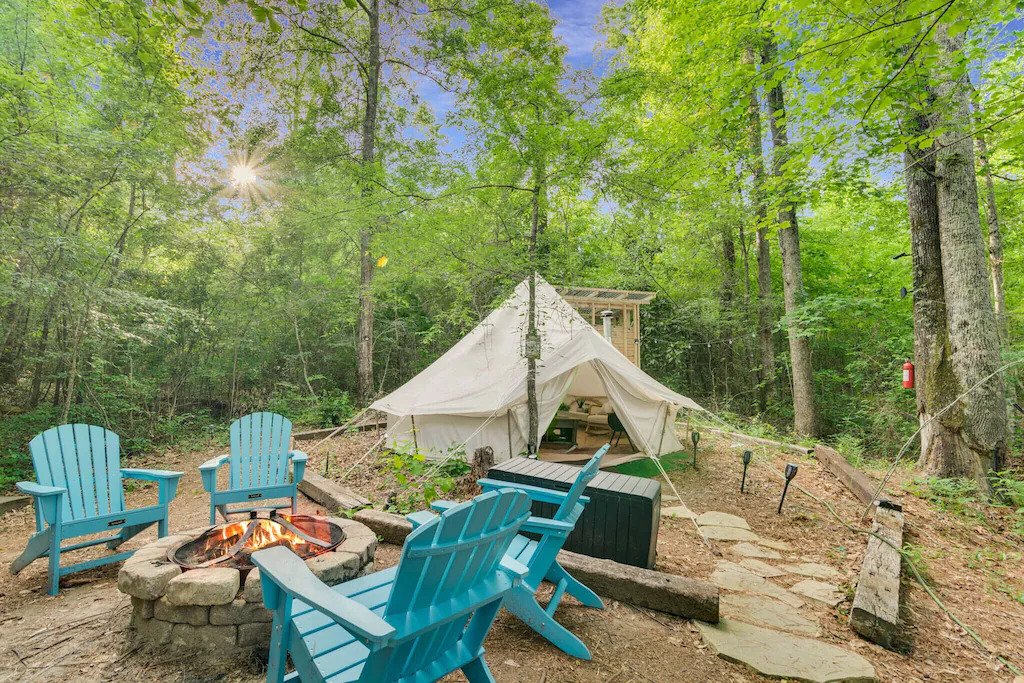 view of the firepit, cute bell tent, and surrounding beautiful woodlamd 