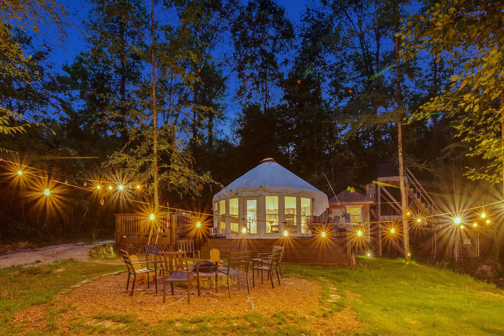 view of the twinkle lights and firepit out front of this spacious yurt. 