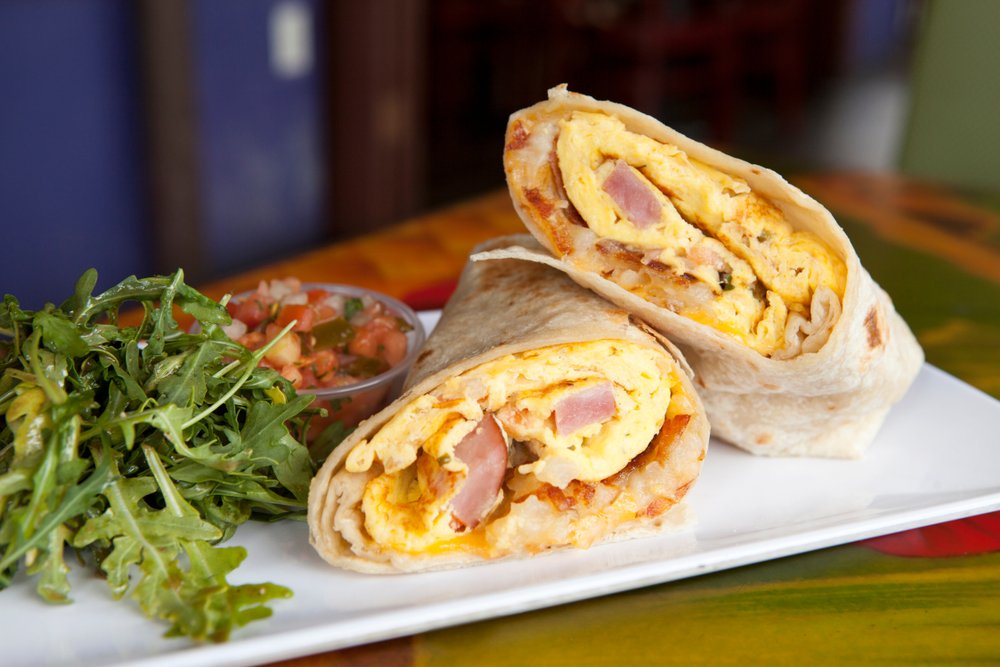 photo of a breakfast burrito cut in half filled with eggs and ham, something you might find at one of the best places for breakfast in Memphis 
