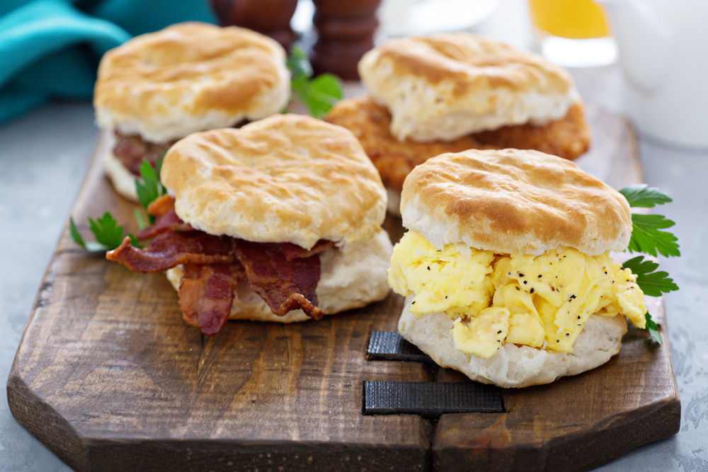 photo of four biscuits on a cutting board. one with bacon, one with eggs, one with sausage, and one with chicken 