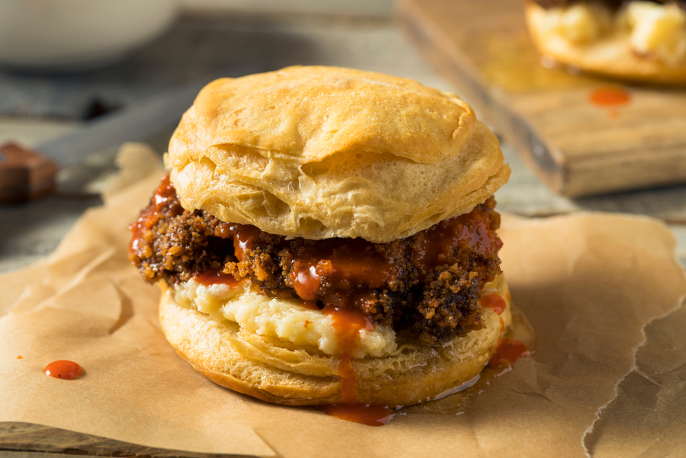 photo of a chicken biscuit with a red sauce drizzling down the sides 