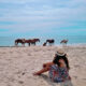 woman with ponies sitting on the beach at one of the best things to do in maryland USA