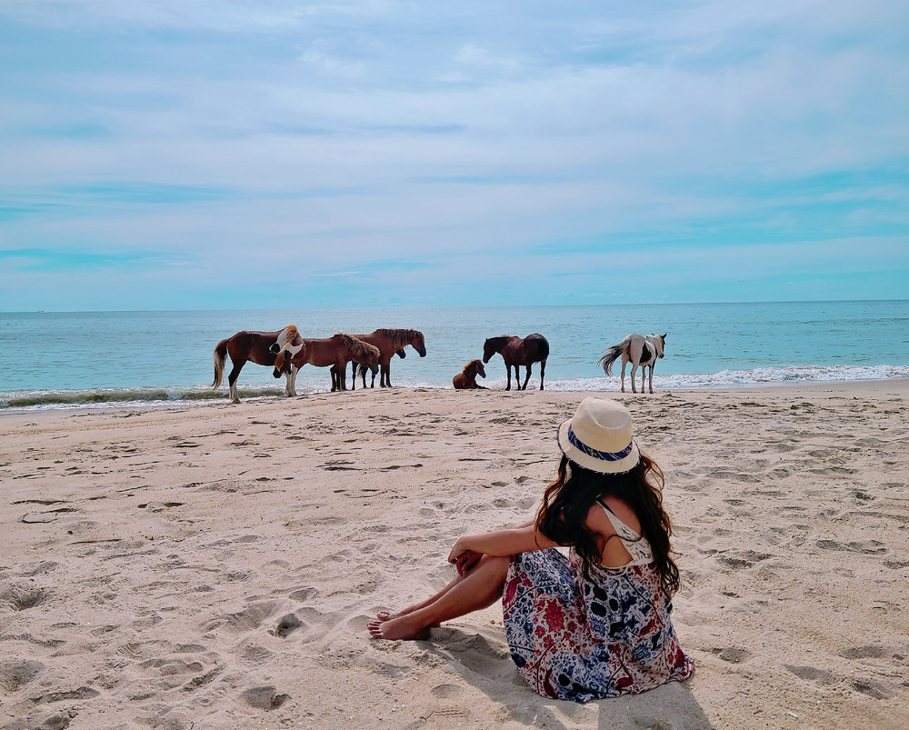 woman with ponies sitting on the beach at one of the best things to do in maryland USA