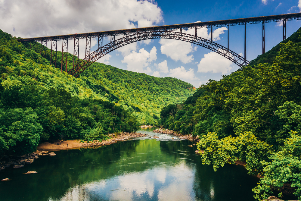 large metal bridge between two mountains over a river