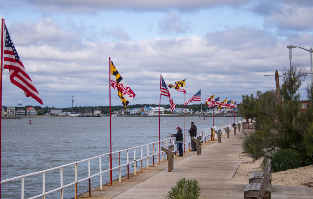 a beautiful view of people fishing on the water with Maryland flags in the back round 