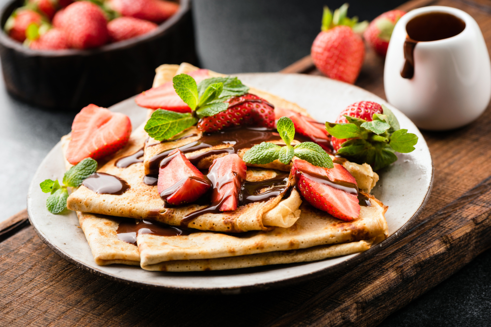 a plate of crepes topped with strawberries and nutella, a bowl of strawberries in the background, bayside skillet, one of the best restaurants in ocean city maryland