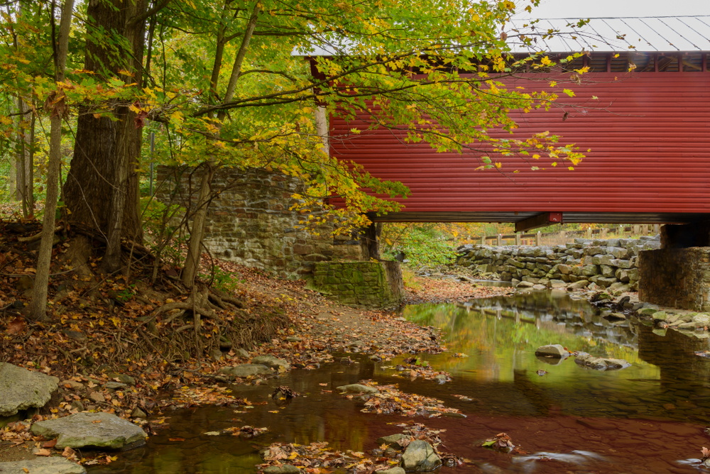 a covered bridge over a river in the woods in fall in thurmont, one of the best small towns in maryland 