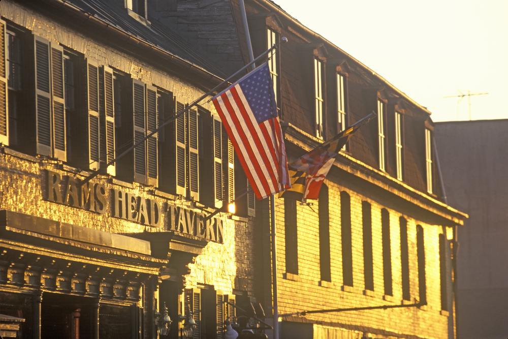 a picture of the rams head tavern, among the best things to do in annapolis, a brick building with an american flag flying, shutters on the windows