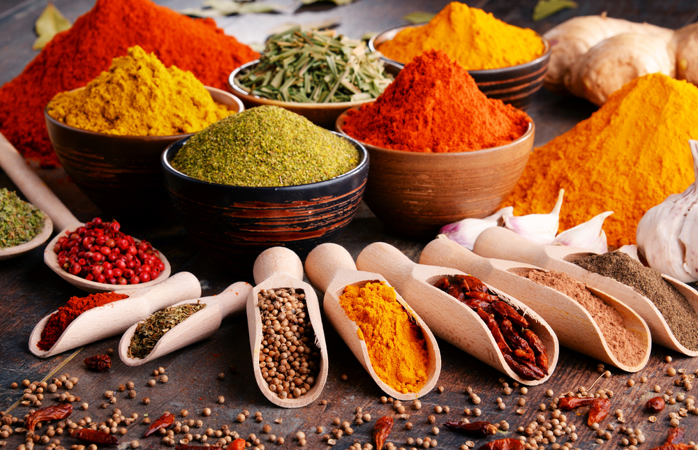 bowls and scoops of spices and herbs sit on a wooden table