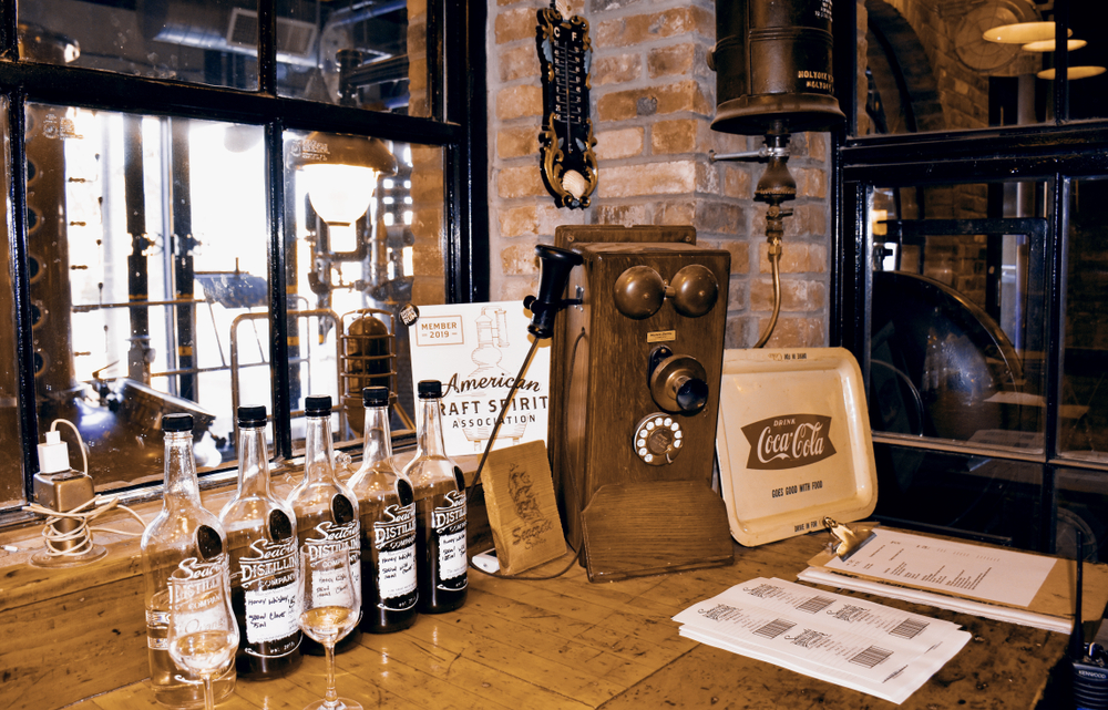 Bottles of alcohol in Seacrets Distilling Company. They are all on a wood table. 