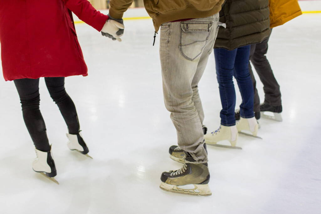 Close up of friends on skating rink. The picturs shows their feets on the ice 