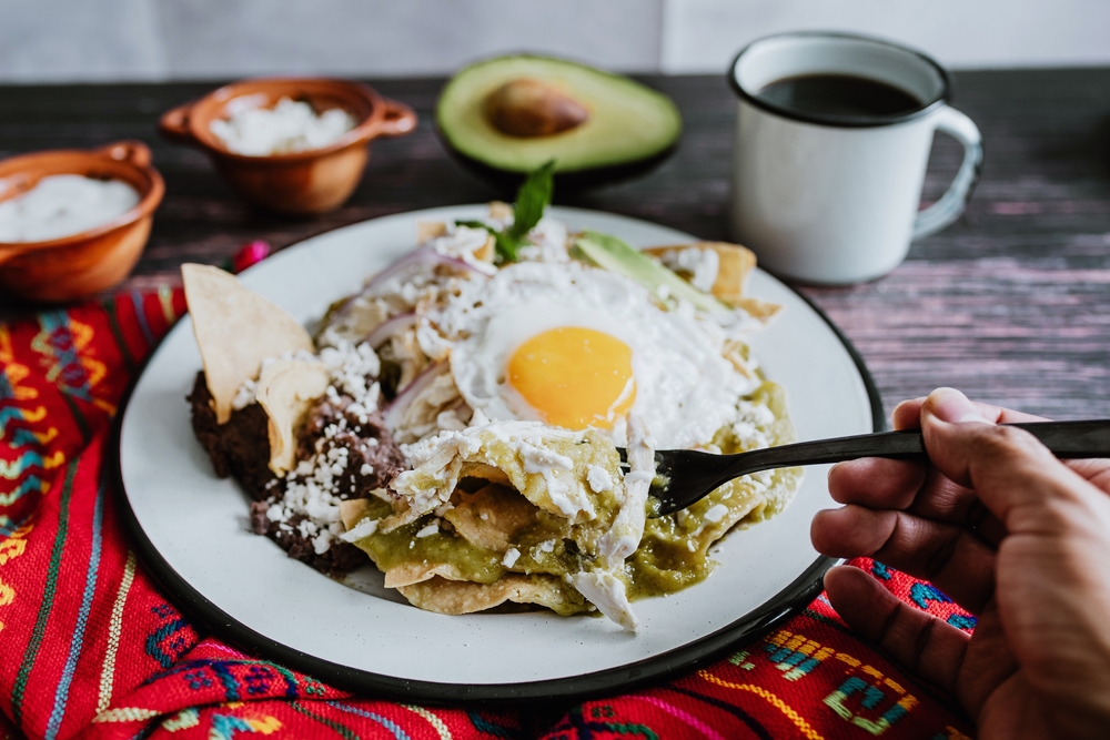 Breakfast nachos anyone? A sunny side up egg sits on a pile of tortilla chips, onion, guac and more