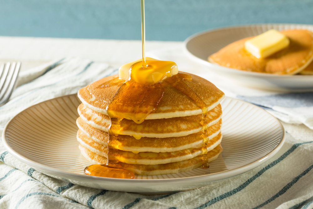A stack of fluffy pancakes drizzled with maple syrup. 