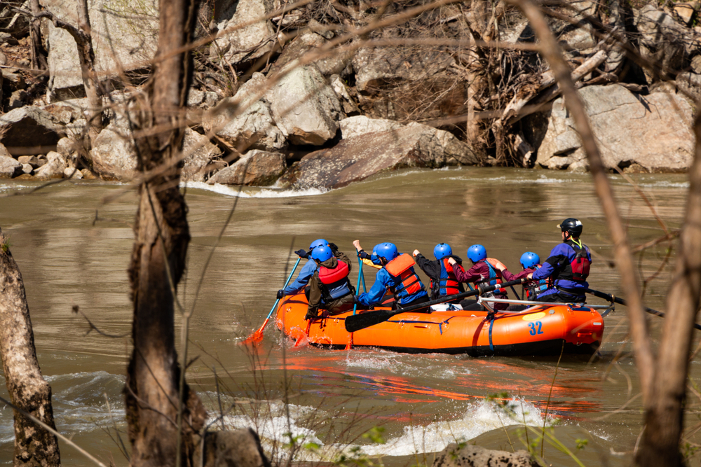 a raft with people on it on the river, white water rafting, one of the best weekend getaways in west virginia