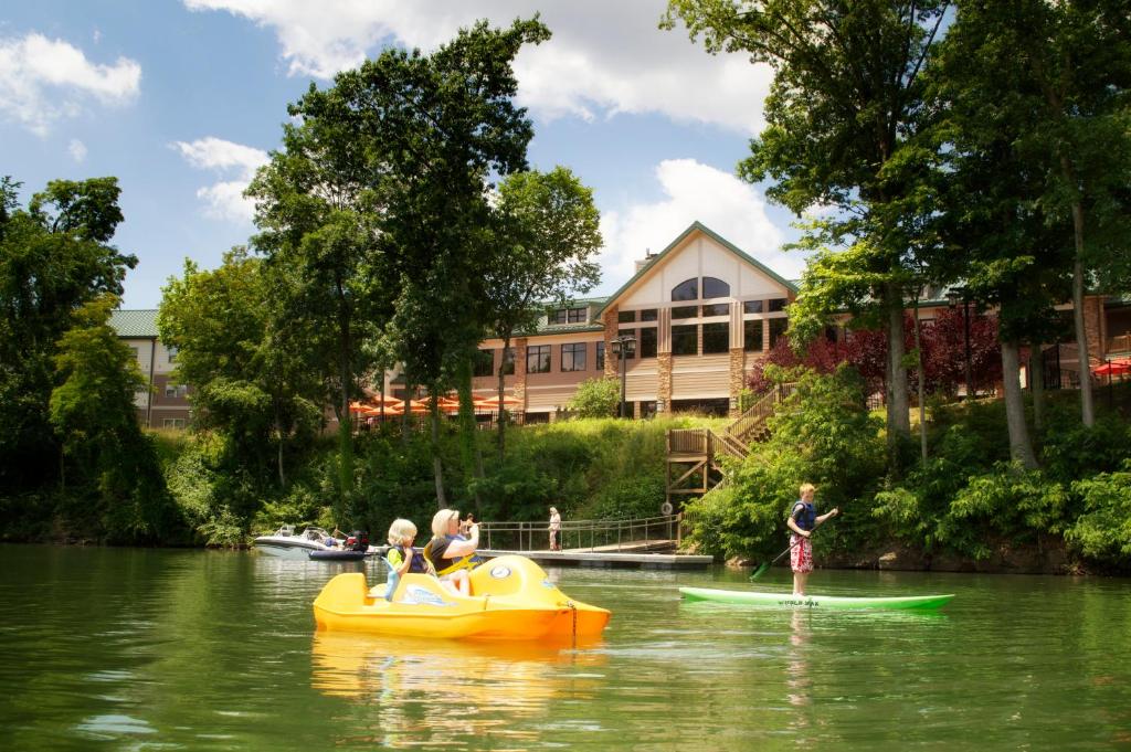 paddleboat and paddleboard in the lake in front of a resort surrounded by trees, among top weekend getaways in west virginia