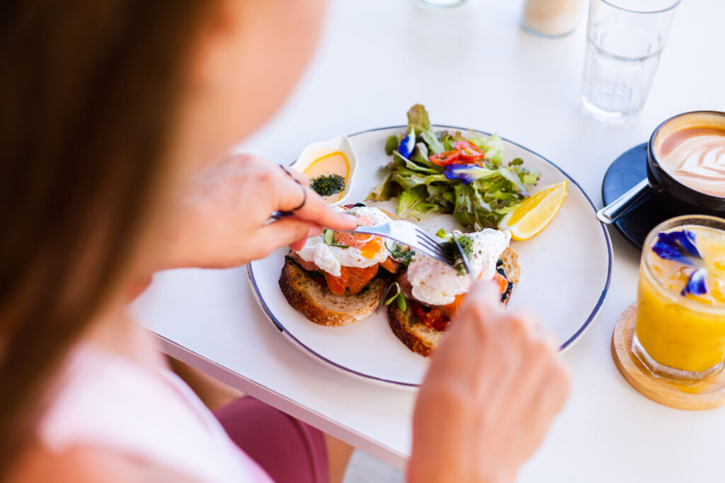 Girl eating outdoor brunch in Austin with a salmon benedict, coffee, and juice