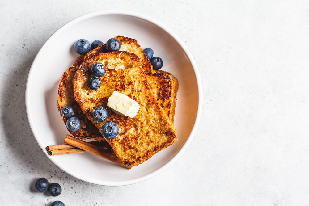 a gorgeous plate of perfectly cooked cinnamon french toast topped with blueberries and butter! a yummy option for the best brunch in Dallas!
