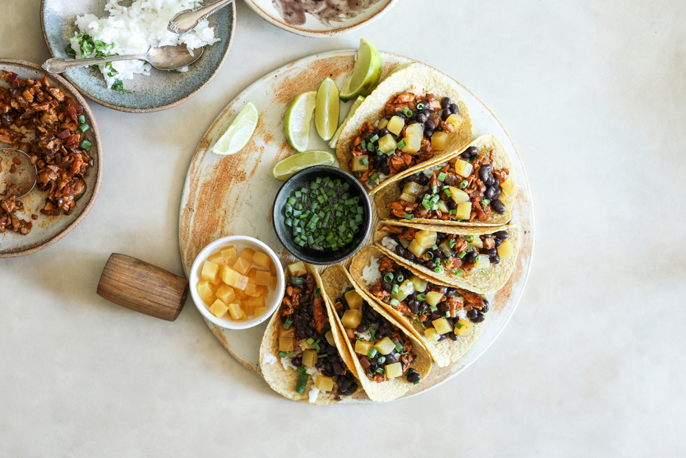 a platter of fresh and vibrant vegan tacos, paired with salsas, veggies, and of course lime wedges to top it off!
