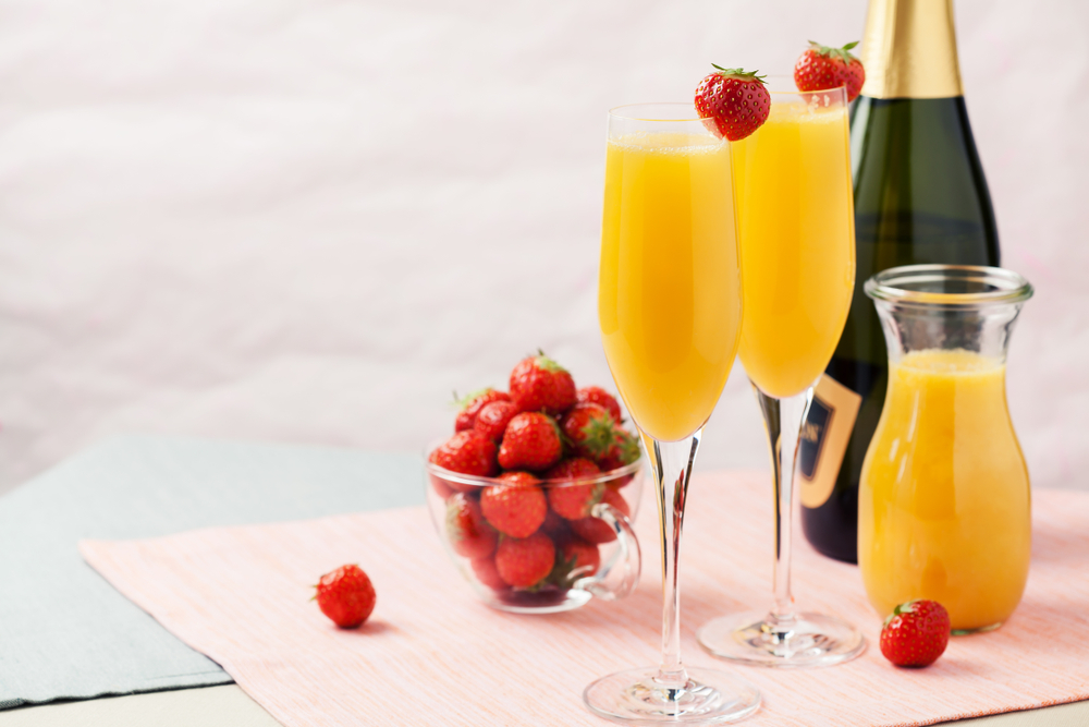 a clean image of ripe strawberries topped on glasses of a brunch staple, mimosas!