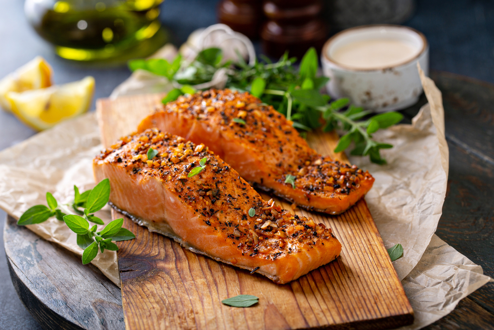 two salmon steaks on a cutting board with fresh herbs