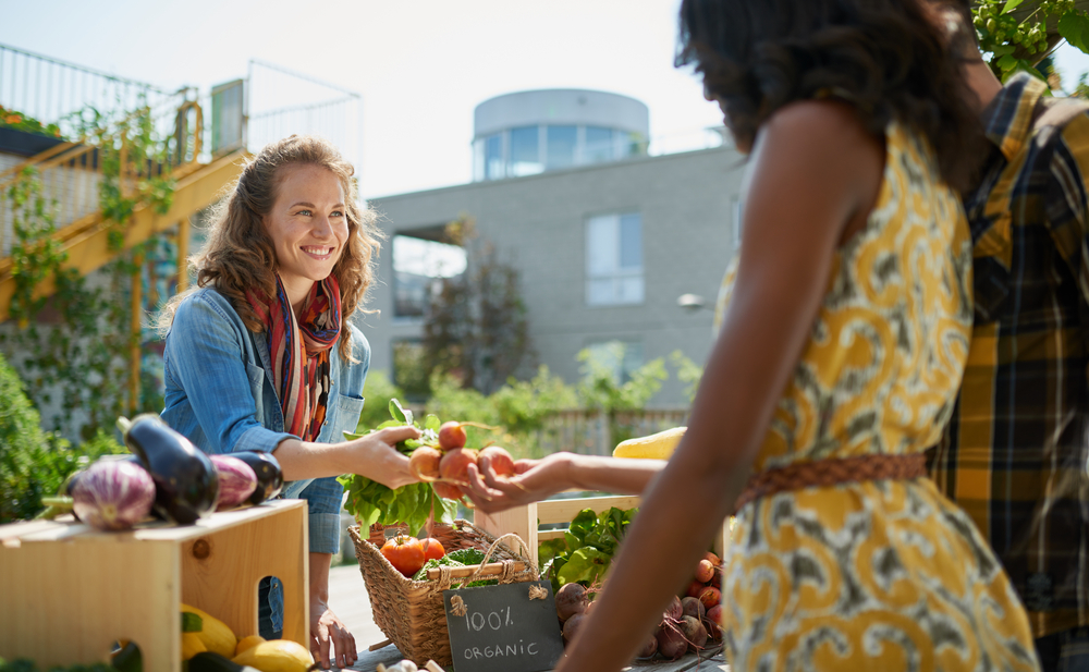 a women handing another women an organic veggie at the Sunday farmer market in St Simons Island