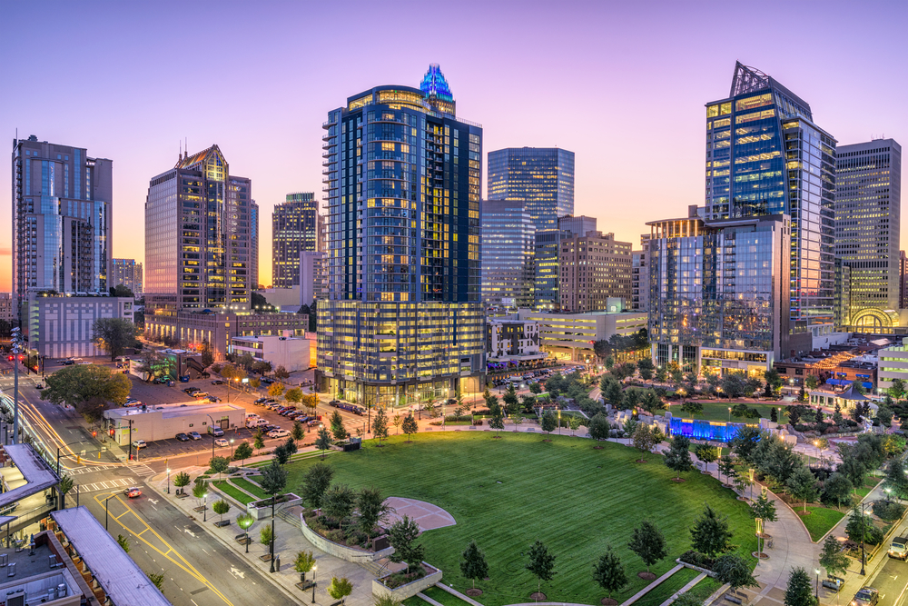 The cityscape of Charlotte North Carolina is stunning at night, with glowing lights of buildings overseeing green parks and streets.