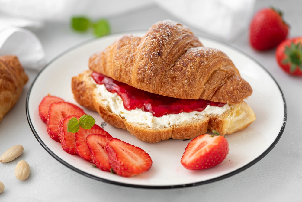 Croissants are always a great option for brunch: this photo features a croissant dusted with powered sugar and filled with cream cheese and strawberry jam. 