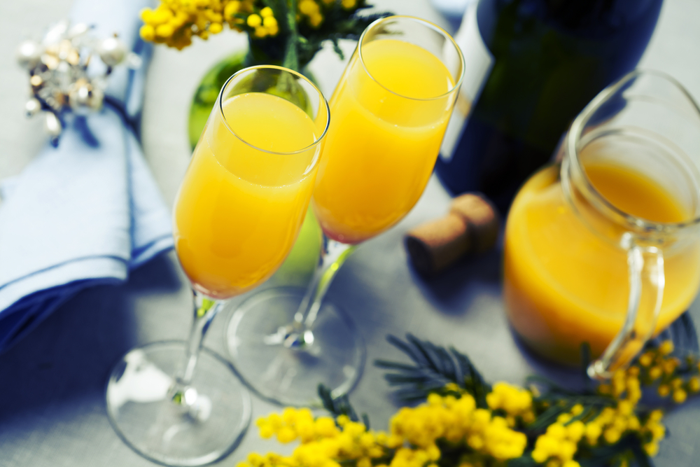 Bottomless Mimosas anyone?! Orange juice, and bubbly fill the two flutes in this photo. 