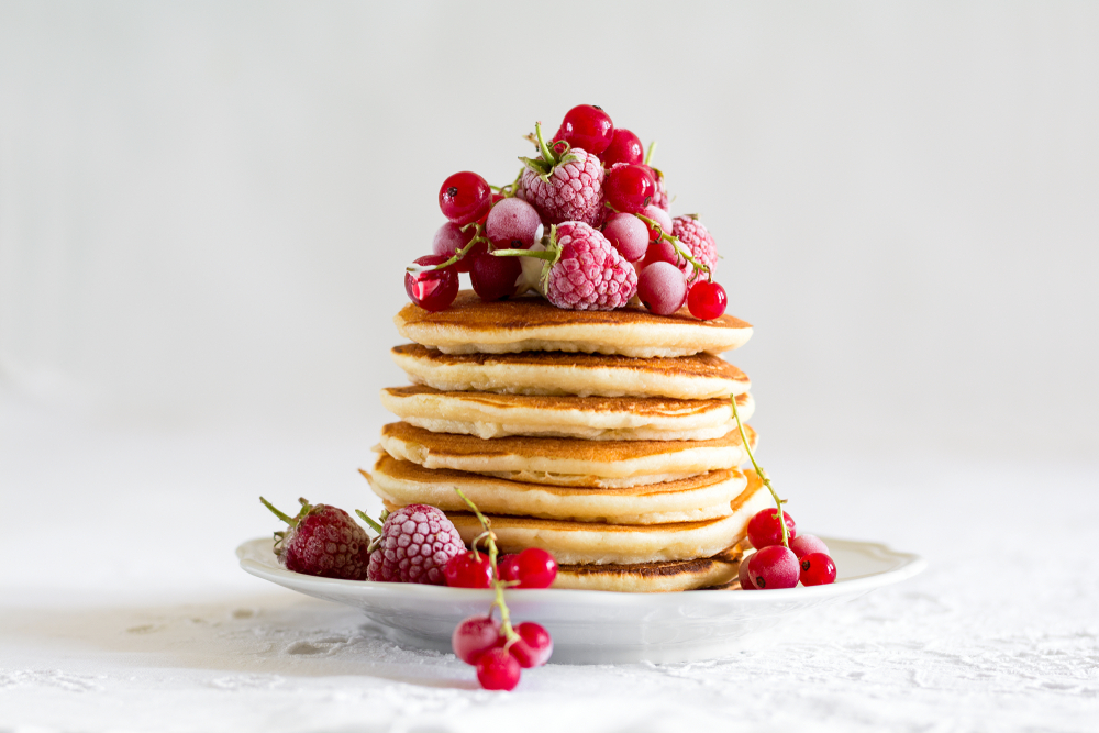 a high stack of pancakes with fruit on top