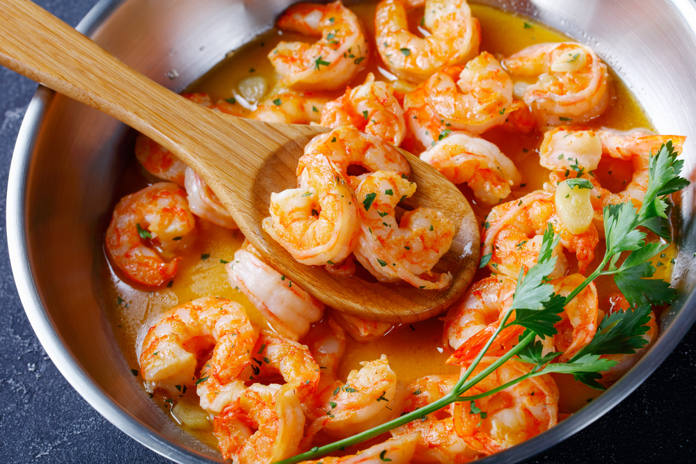 a big pan cooking shrimp with butter and spices. fresh shrimp is some of the best seafood in savannah 