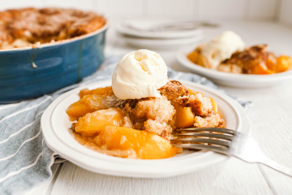 Plate of peach cobbler with vanilla ice cream on top.