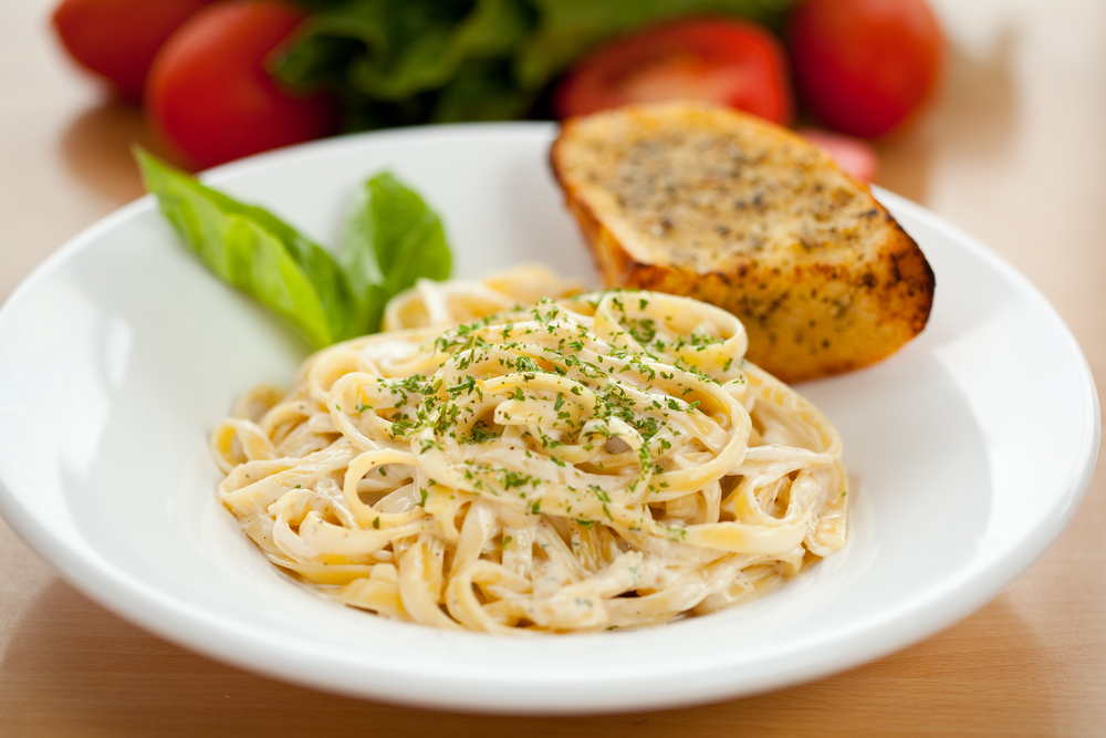 A bowl of plain fettuccine alfredo with slices of garlic bread, like that served at Sal's, one of the best restaurants in Roanoke for Italian food.