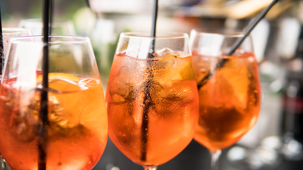 Three glasses of orange Aperol Spritz cocktails.