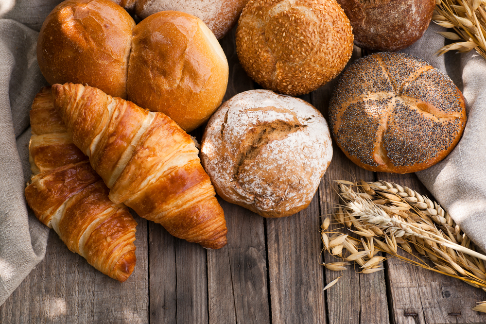 baked goods like croissants and bread rolls with wheat around them. 