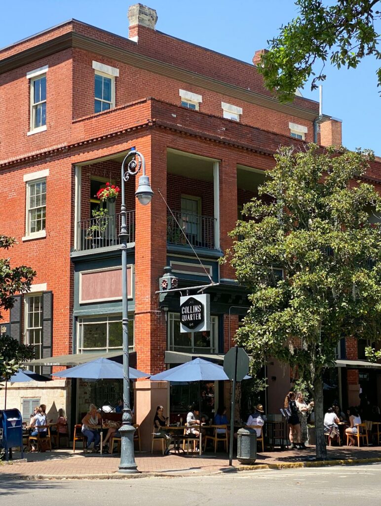 The brick exterior of Collins Quarter with people dining outside.