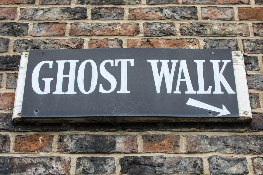 A sign labeling a meeting point for a walking ghost tour shows the beginning of haunting fun! 