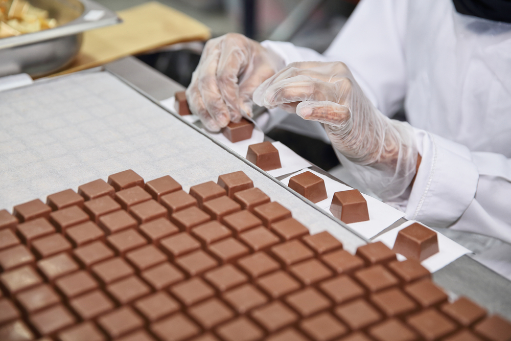 a women in a white coat making chocolate for a tour in Dallas for adults 