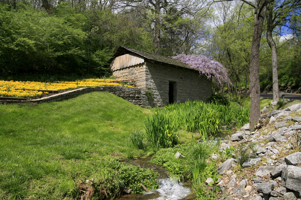 Flowers bloom around an old stone springhouse at Gaylord Springs Golf Links, one of the best golf courses in Tennessee.