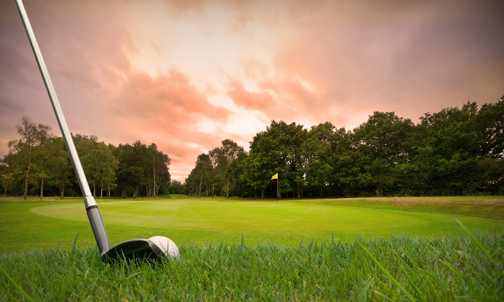 A sunrise golfer teeing off on the green