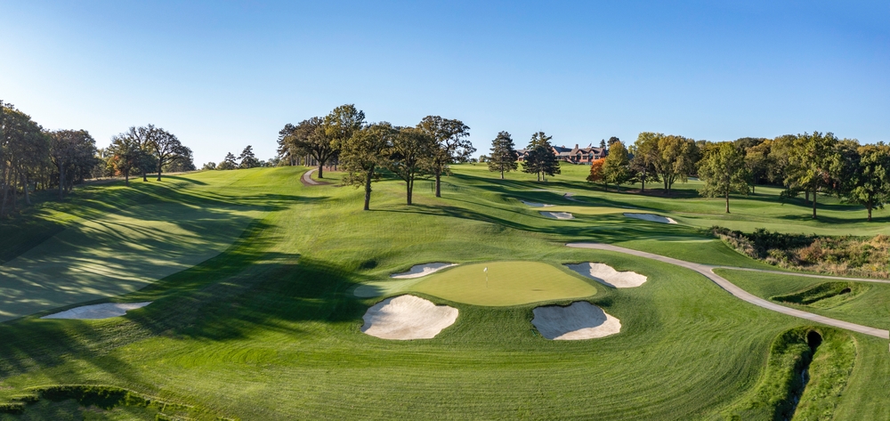 A hilly course with sand bunkers and trees and cart path