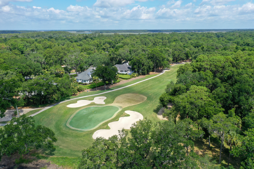 an ariel view of a golf course with sand bunkers surrounded by homes and mature trees