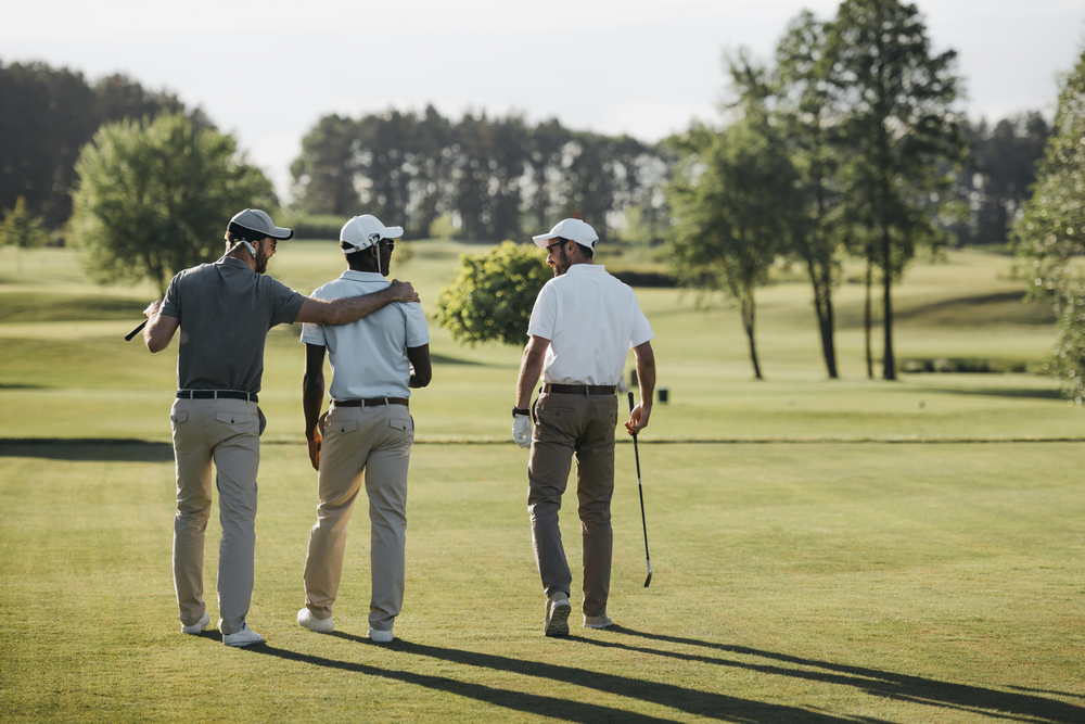 Three men walking along a golf course