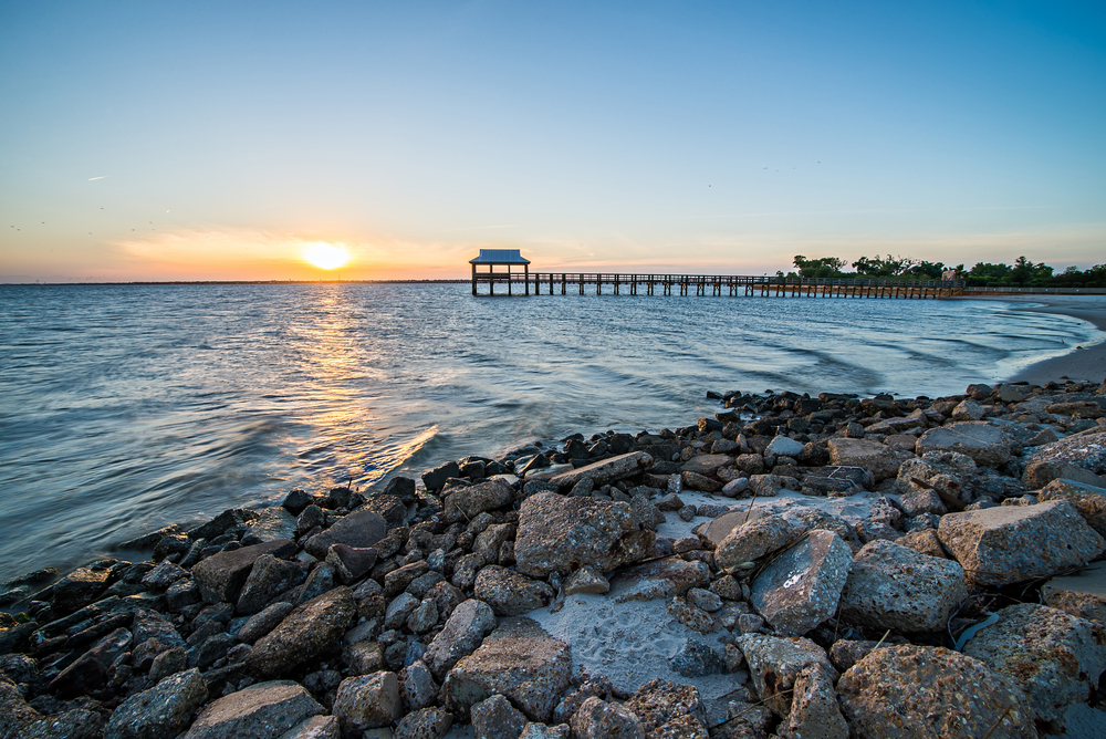 rocky coastline and wooden boardwalk reaching out over the water leading to a gazebo, best things to do in pass christian mississippi