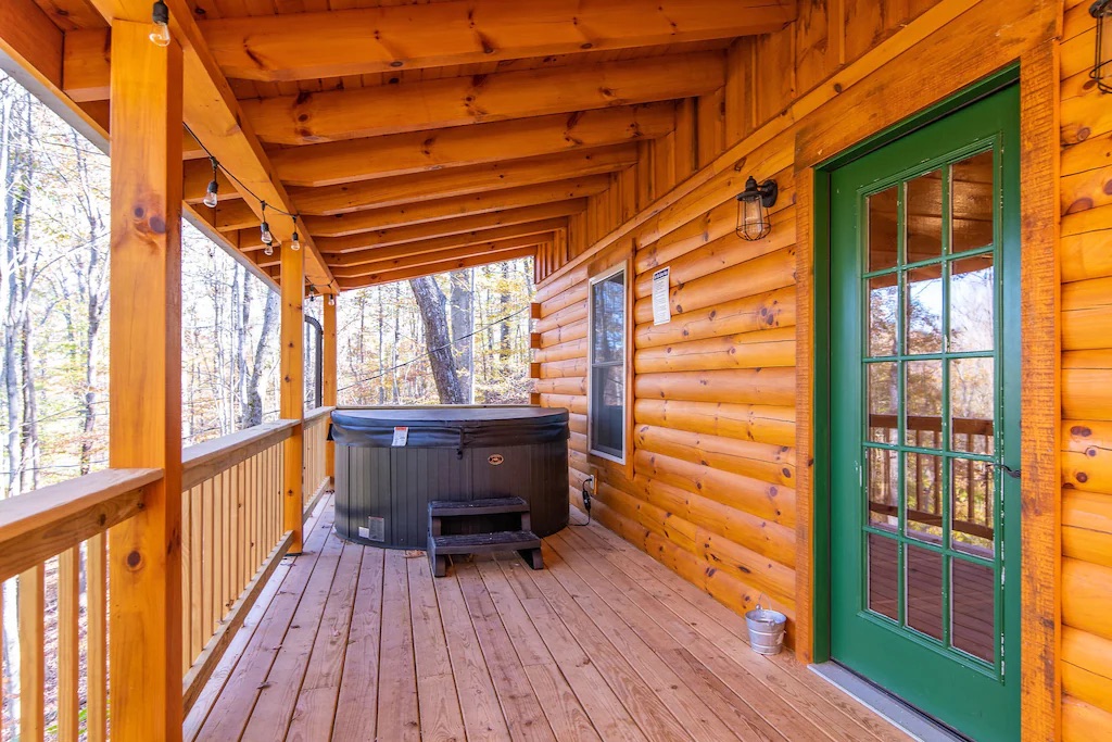 A green door to outdoor deck featuring knotty pine and a hot tub at the far end