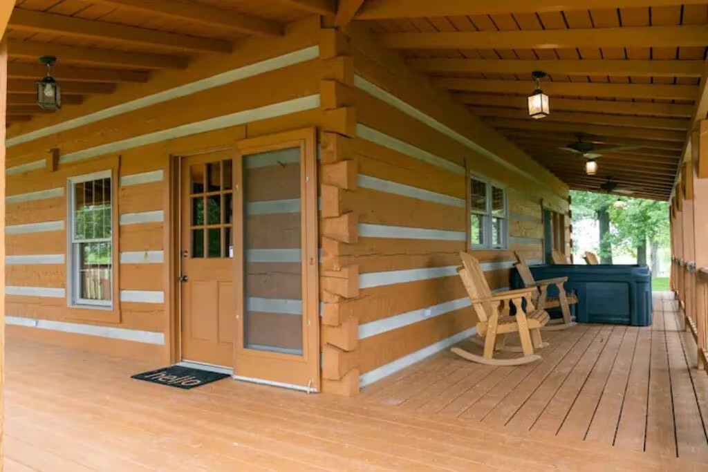 A corner view of the large porch featuring hot tub and wooden rocking chairs at the cabin with hot tubs in Kentucky